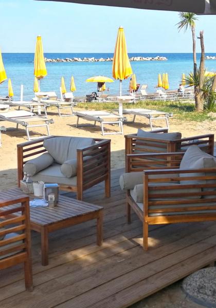 Spiaggia con ombrelloni gialli e sedie a sdraio, area relax con divani.