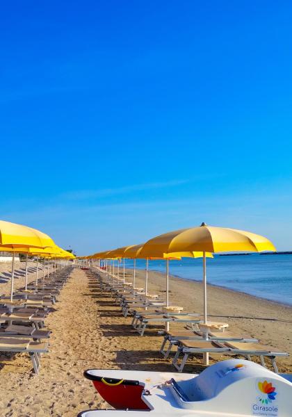 Spiaggia sabbiosa con ombrelloni gialli e lettini, mare calmo.